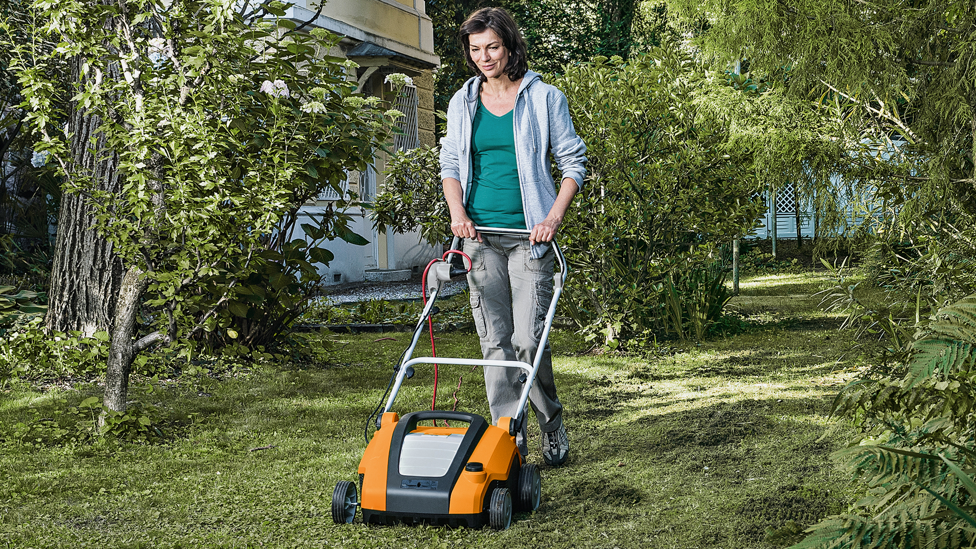 Frau arbeitet mit STIHL Vertikutierer RLE 240 im Garten