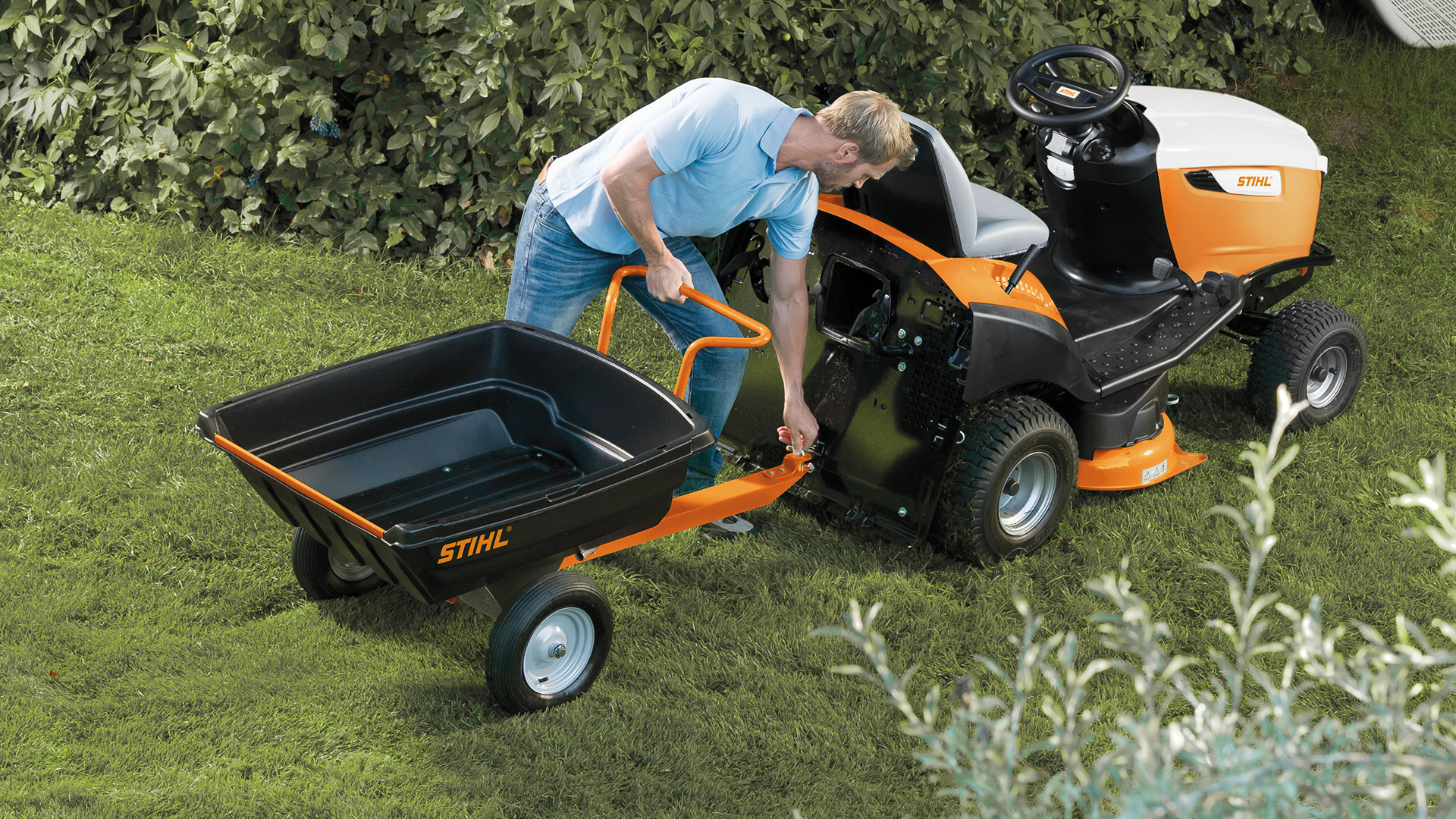 Mann montiert STIHL PICK UP 300 Anhänger an STIHL Aufsitzmäher RT 5097
