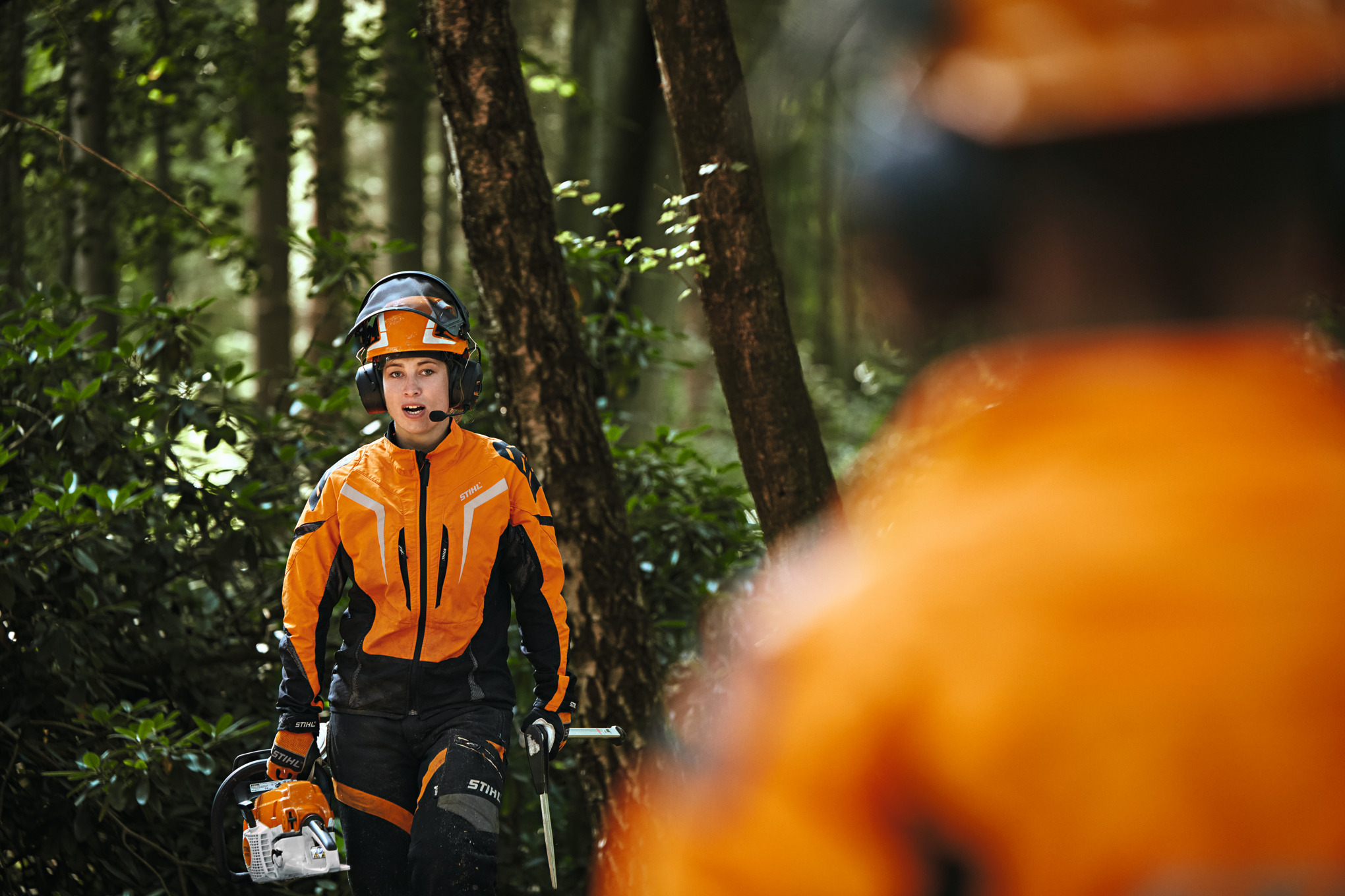 Két STIHL védőruházatot viselő erdészeti dolgozó STIHL ADVANCE ProCOM konferenciarendszerrel 