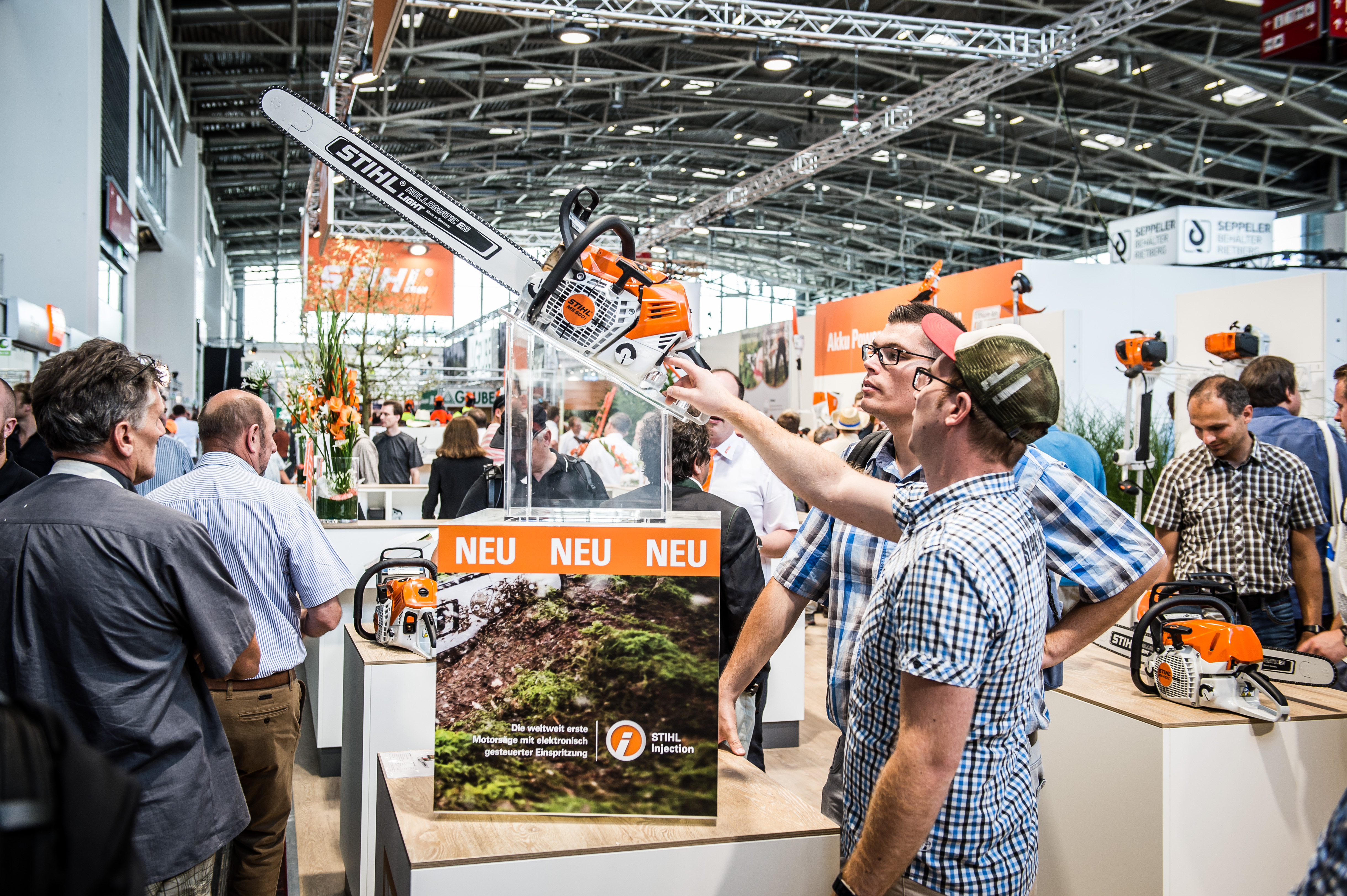 A STIHL stand látogatói megnézik a termékújdonságokat, köztük egy STIHL láncfűrészt. 