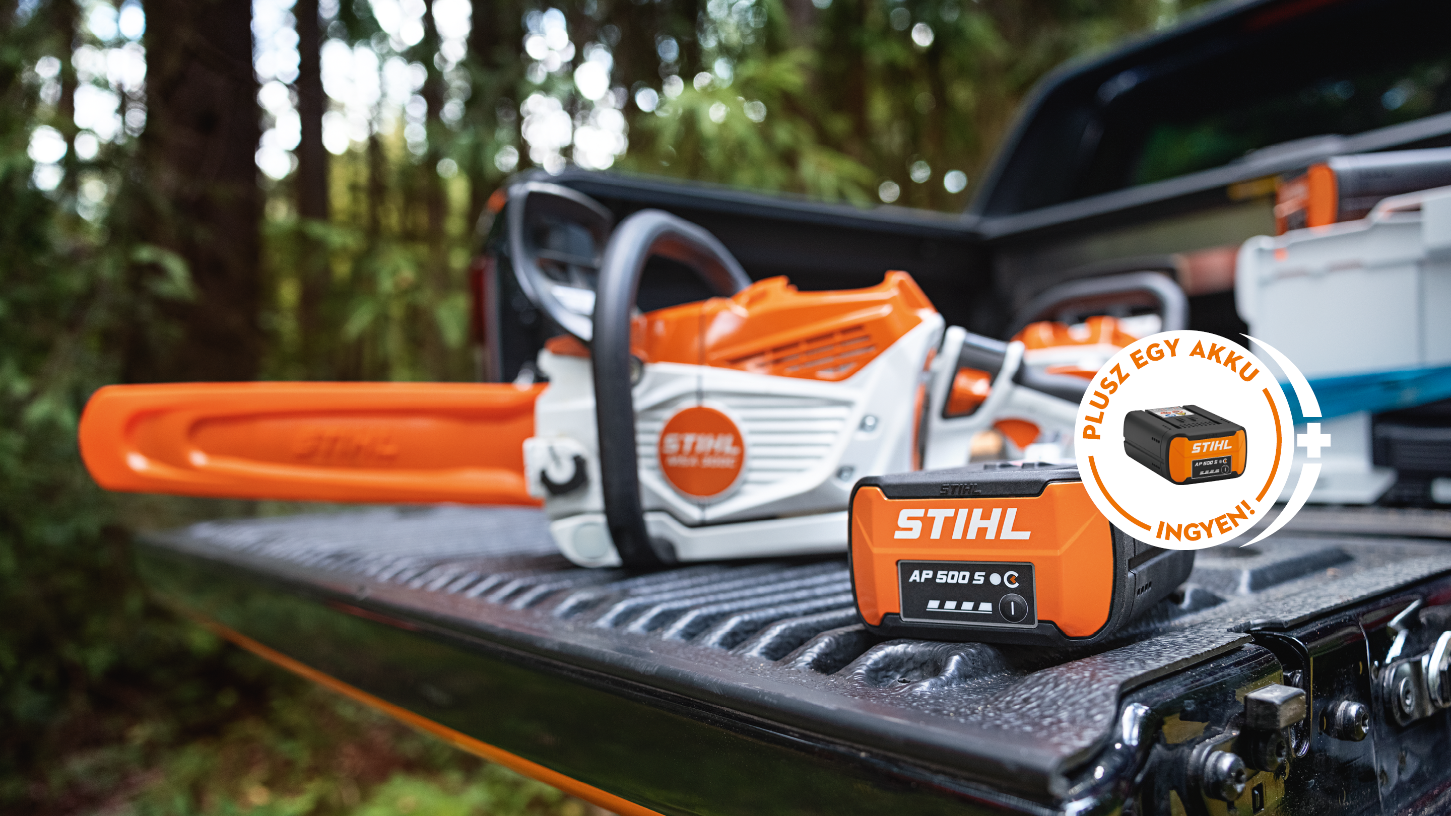 STIHL AP 500 S akkumulátor egy pick-up rakodófelületén az új STIHL MSA 300 akkumulátoros motorfűrésszel együtt, valamint egy promóciós anyag STIHL akkumulátorral és a „Get a free battery” felirattal.