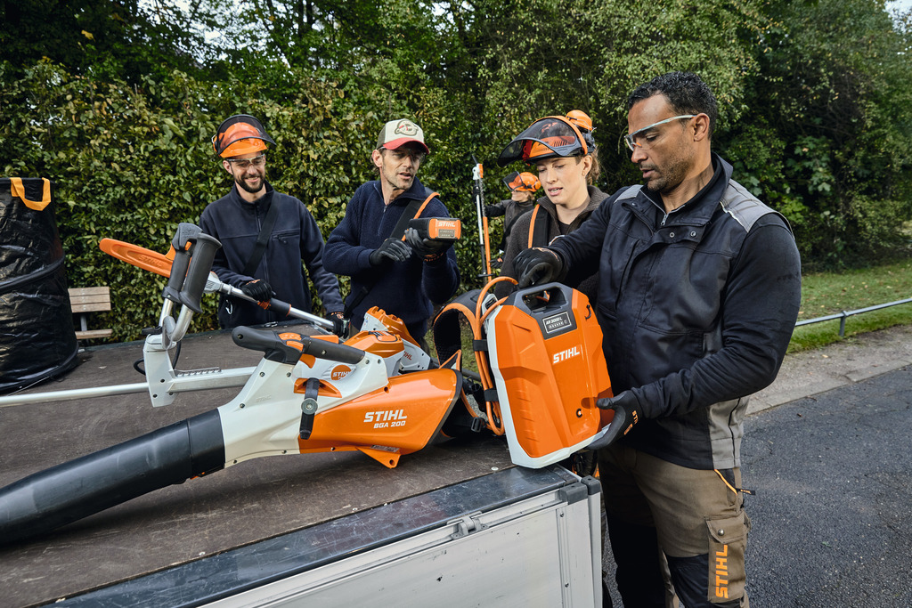 Egy tájépítészeti szakemberekből álló csapat a STIHL professzionális akkumulátoros berendezéseit rakja ki egy jármű rakodóteréből.